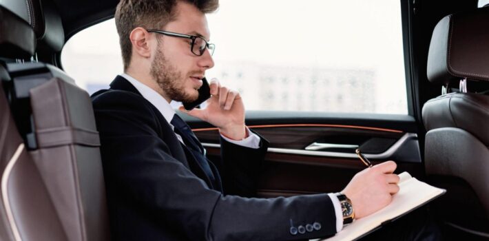 businessman-writing-in-notebook-in-luxury-car