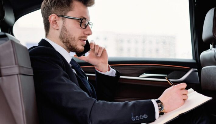 businessman-writing-in-notebook-in-luxury-car